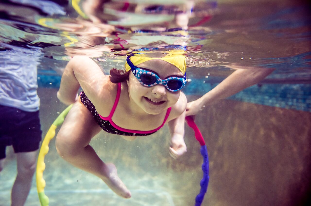Toddler swimming through a hoop underwater at Blue Wave