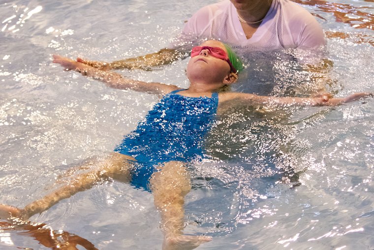 A child is floating on her back in water with confidence