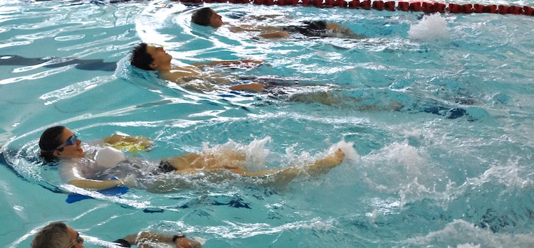 Adults learning to swim backstroke in swimming lessons