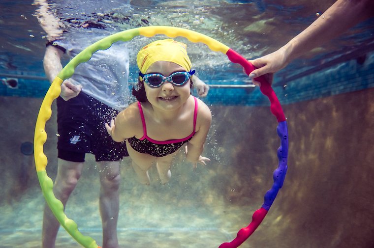 A 3 year old is doing a swimming lessons at Blue Wave Swim School