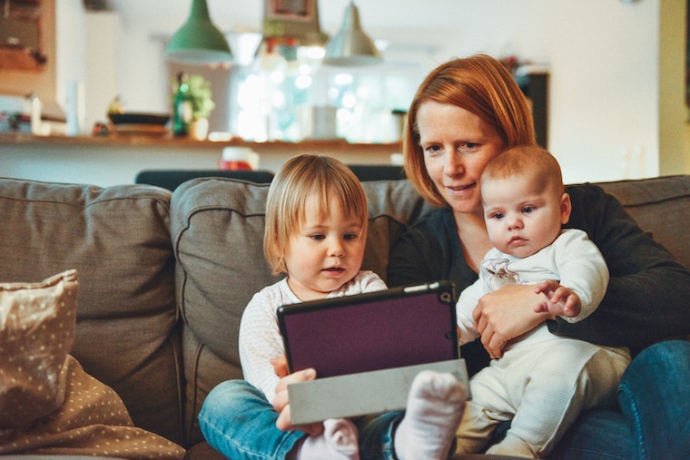 a mum and two children watch a tablet at home