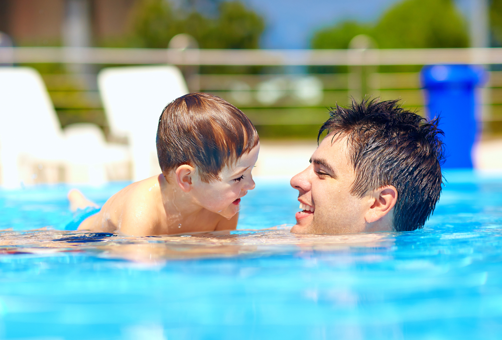 Father and son swimming in a swimming pool on holiday