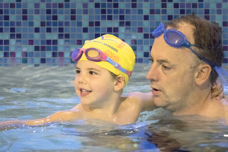A father with his toddler at toddler swim class at Blue Wave Swim School